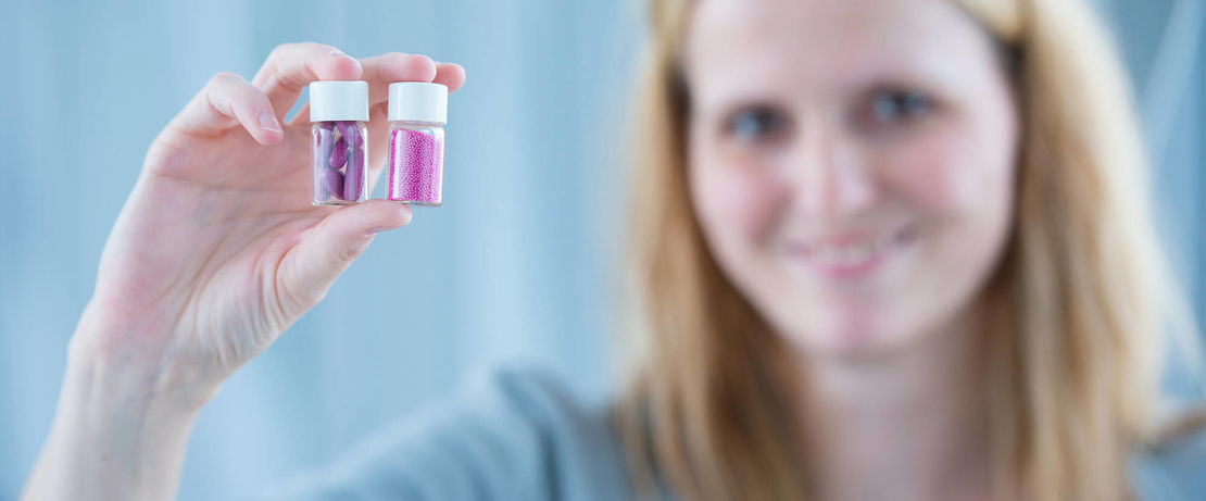 Woman holding two glasses with capsules and polymers