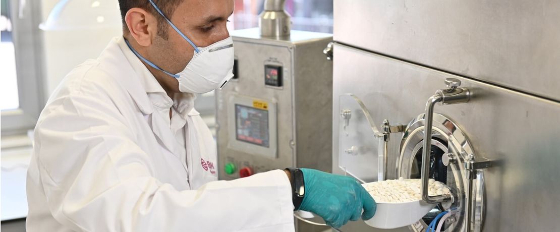 Man adding pills into a coating machine.